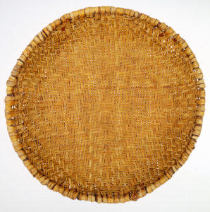 Round, flat baskit, woven, golden in color