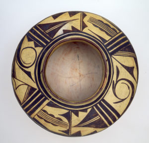 Top down view of a round jar, gold with black geometric designs