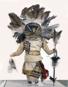 Doll with feathered large headdress and staff